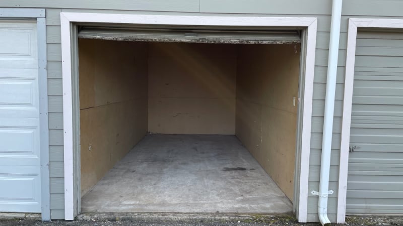 Interior of a small self-storage unit with plywood walls and concrete floor at J & J Mini-Storage